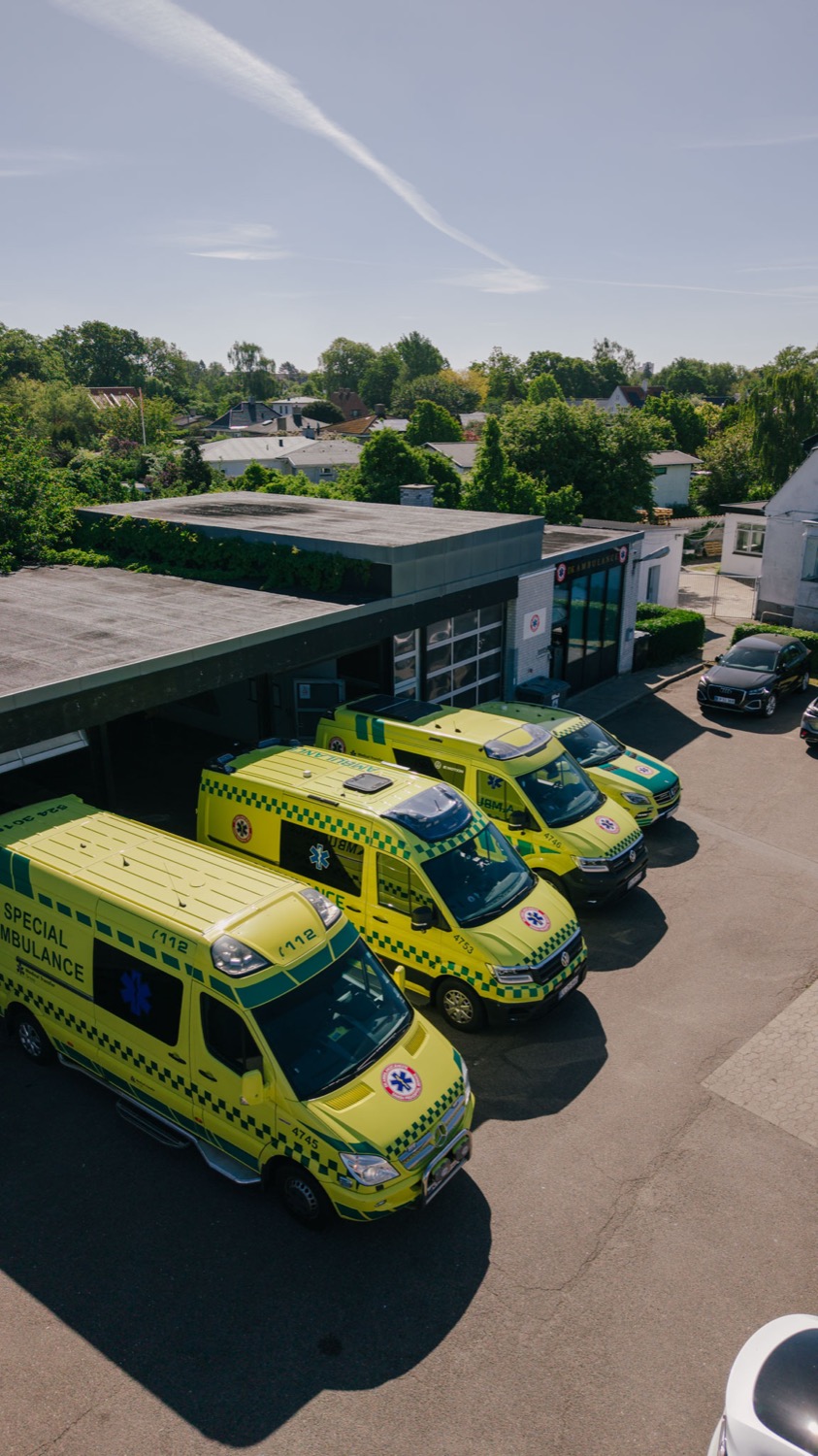 Dronefoto af DK Ambulancetjenestes vognpark foran basen
